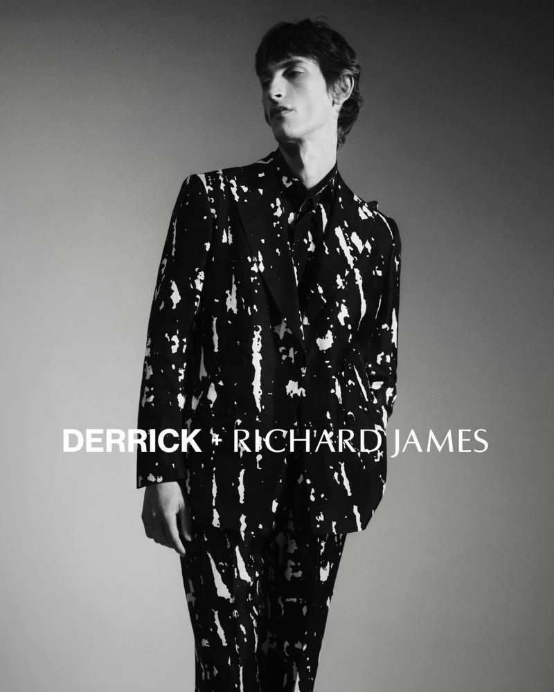 Model Theodor Pal wearing a black and white paint-splattered tailored suit in the Derrick x Richard James 2025 campaign.