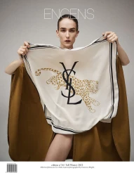 Model Atherton Johnson holds a white Yves Saint Laurent silk scarf printed with a leopard in front of a brown cape.