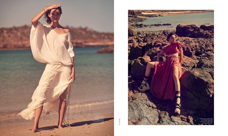 Two fashion models pose on the beach and rocks near the water. The model on the left is in a white dress and the model on the right is in a red skirt and top.