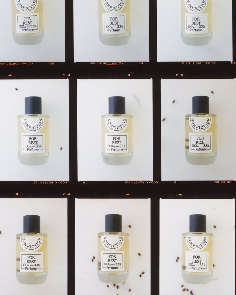 Multiple perfume bottles on a film strip background, featuring the Nonfiction brand, 'For Rest' scent, in a clean, minimalist composition.