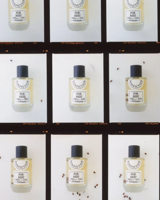 Multiple perfume bottles on a film strip background, featuring the Nonfiction brand, 'For Rest' scent, in a clean, minimalist composition.