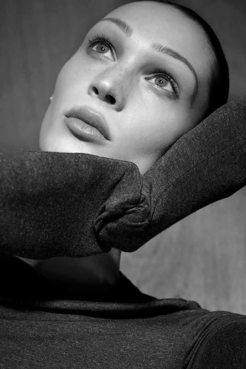 Black and white close-up portrait of an adult woman with freckles looking upward, wearing a gray turtleneck sweater.