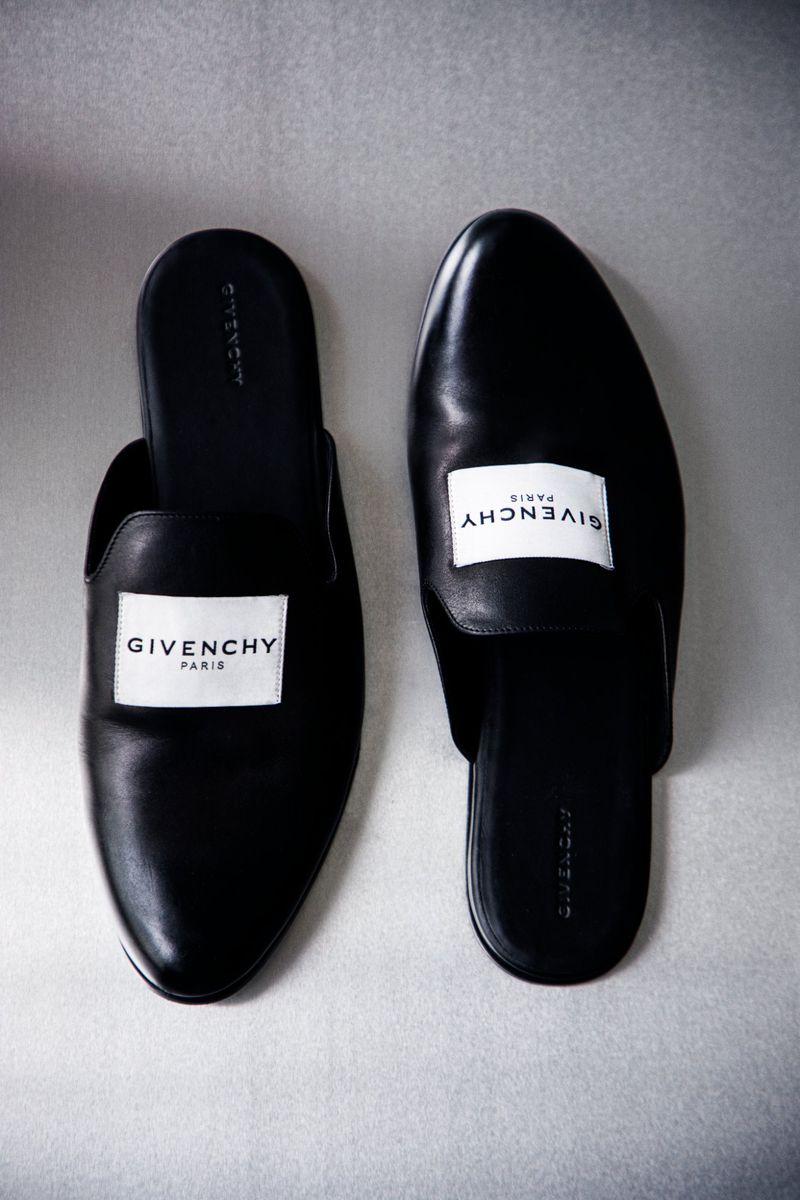 Studio shot of a pair of black leather Givenchy slide shoes with a white label. Minimalist fashion product photography.