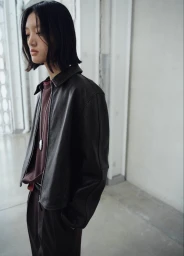 Model Yilan Hua wearing a black leather jacket and burgundy top in a minimalist interior for Mango Strictwear Burgundy.