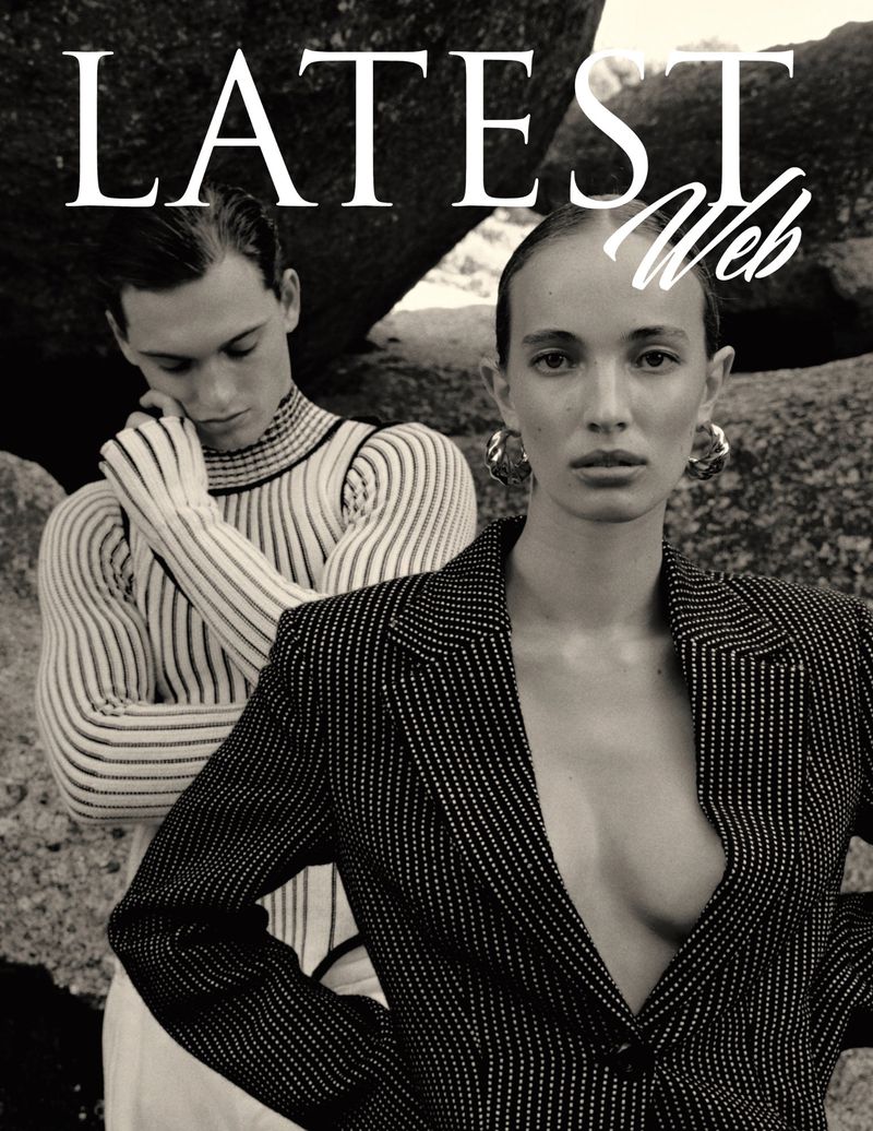 Editorial fashion shot: two models, one in striped blazer and earrings, the other in a striped turtleneck, posed against a rock background.
