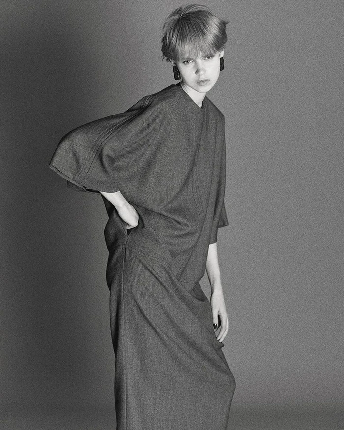 Model wearing a dark long-sleeved dress against a seamless grey backdrop for D Repubblica