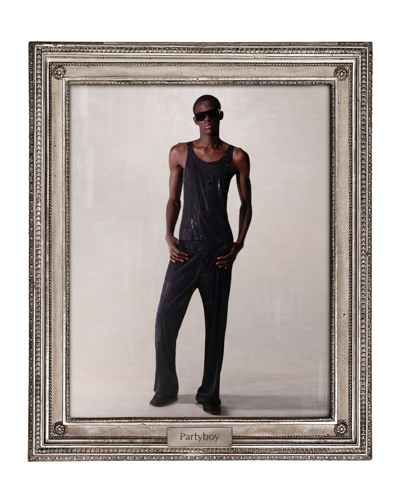Person in black jumpsuit posing in silver picture frame against neutral background, illuminated by direct lighting and cool tones.