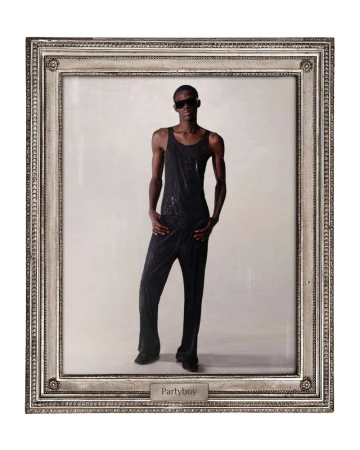 Person in black jumpsuit posing in silver picture frame against neutral background, illuminated by direct lighting and cool tones.