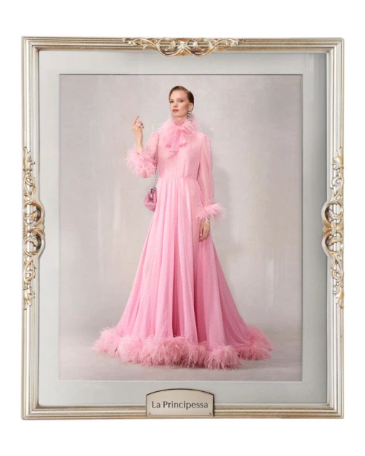 Woman in a pink feathered gown posing inside an ornate silver frame against a light background. Fashion shot, studio lighting.