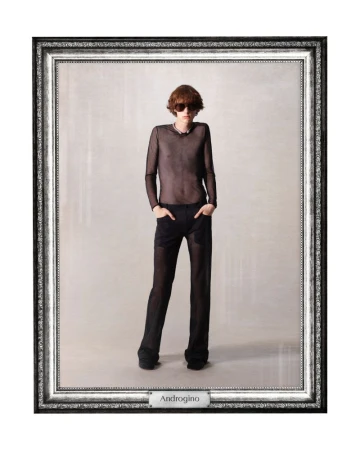A model in a mesh top and trousers poses in a studio, framed for a fashion editorial. The composition features a neutral backdrop.