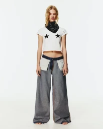 Model wearing a white t-shirt with star prints and wide-leg denim pants against a white background for Pull & Bear.