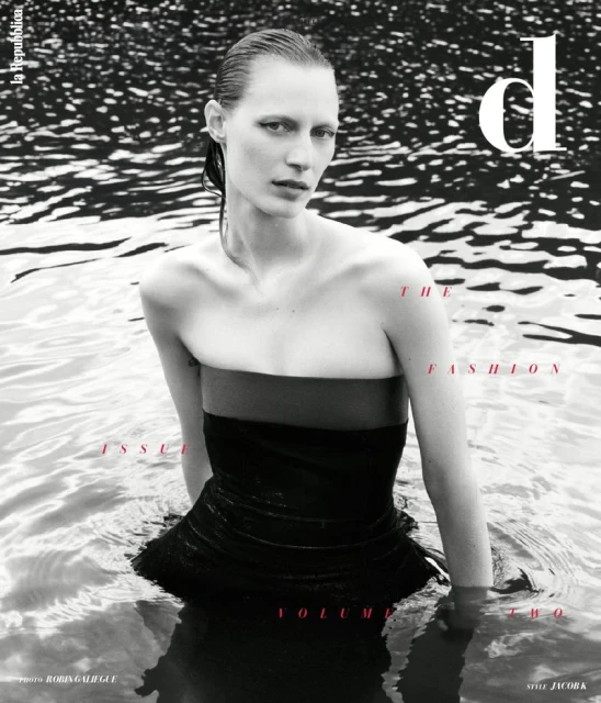 Fashion magazine cover featuring a woman in water wearing a dark dress, promoting the fashion issue, volume two, with water background.