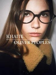 Close-up portrait of a model wearing black glasses and a dark collared jacket for Khaite x Oliver Peoples campaign