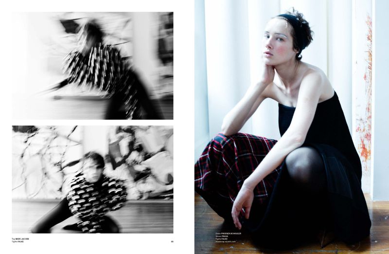 Woman poses in black dress with plaid fabric. Fashion editorial image features indoor setting with window, posing, and subdued lighting.
