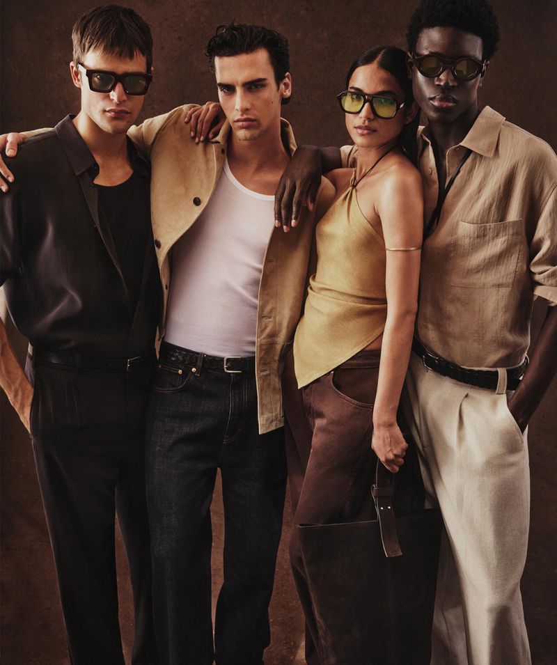 Four diverse fashion models in sunglasses and stylish clothes pose in a studio with a seamless backdrop for a fashion campaign.