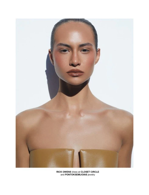 Portrait of a model in a tan strapless dress against a white background, showcasing fashion and beauty in a studio setting.