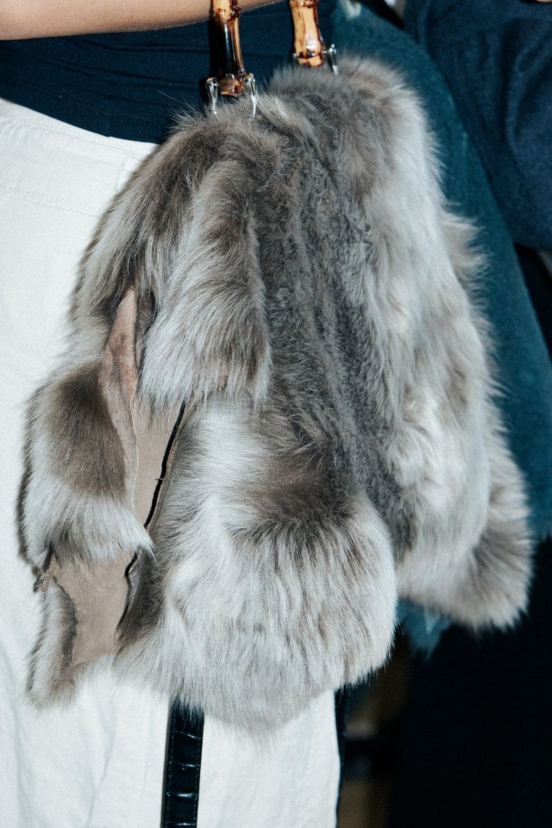 Fur handbag with bamboo handles featuring grey and beige tones. Fashion accessory made of fur and leather textures.