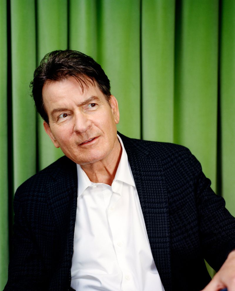 Portrait of adult male in a dark suit and white shirt, looking off-camera in an indoor setting with a green background.