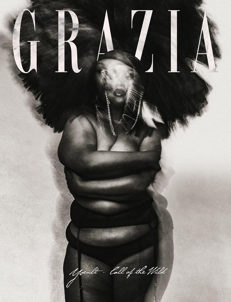 Black and white fashion portrait of an adult female with a dramatic hairstyle posing against a textured background with 'Grazia' text overlay.