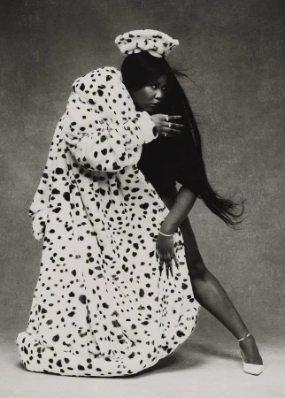 Singer Yseult posing dynamically in an oversized dalmatian-print faux fur coat and matching beret against a textured studio backdrop.