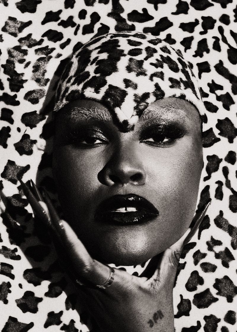 Striking black and white portrait of an African American woman with flawless skin, glossy black lips, and a cheetah print head covering.
