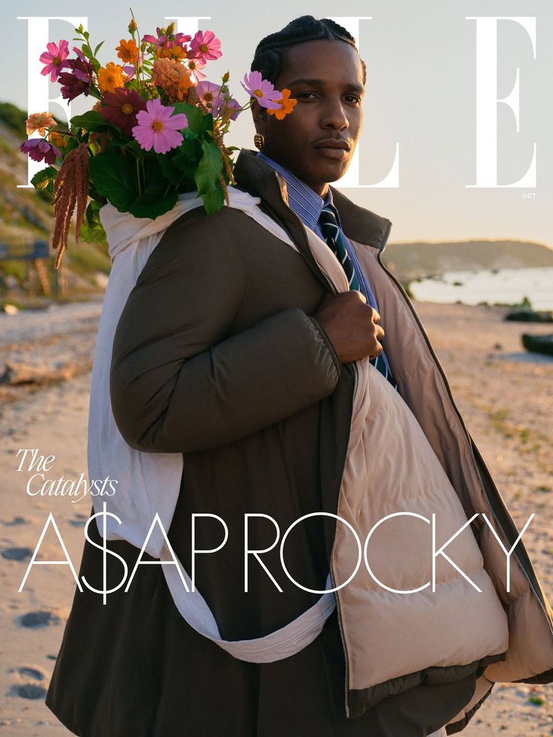 A$AP Rocky poses on a sandy beach, wearing a green puffer jacket and flowers, for an Elle magazine cover photo.
