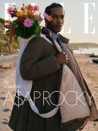 A$AP Rocky carrying a large white sack filled with colorful flowers on a sandy beach at sunset for Elle U.S.