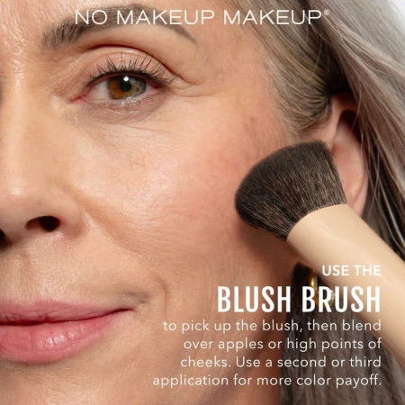 Close-up shot of an adult woman applying blush with a makeup brush.  The model is demonstrating a no-makeup makeup look.