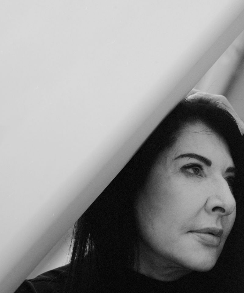 Monochrome portrait of a mature woman with dark hair and light skin in front of a white background, captured in a close-up shot.