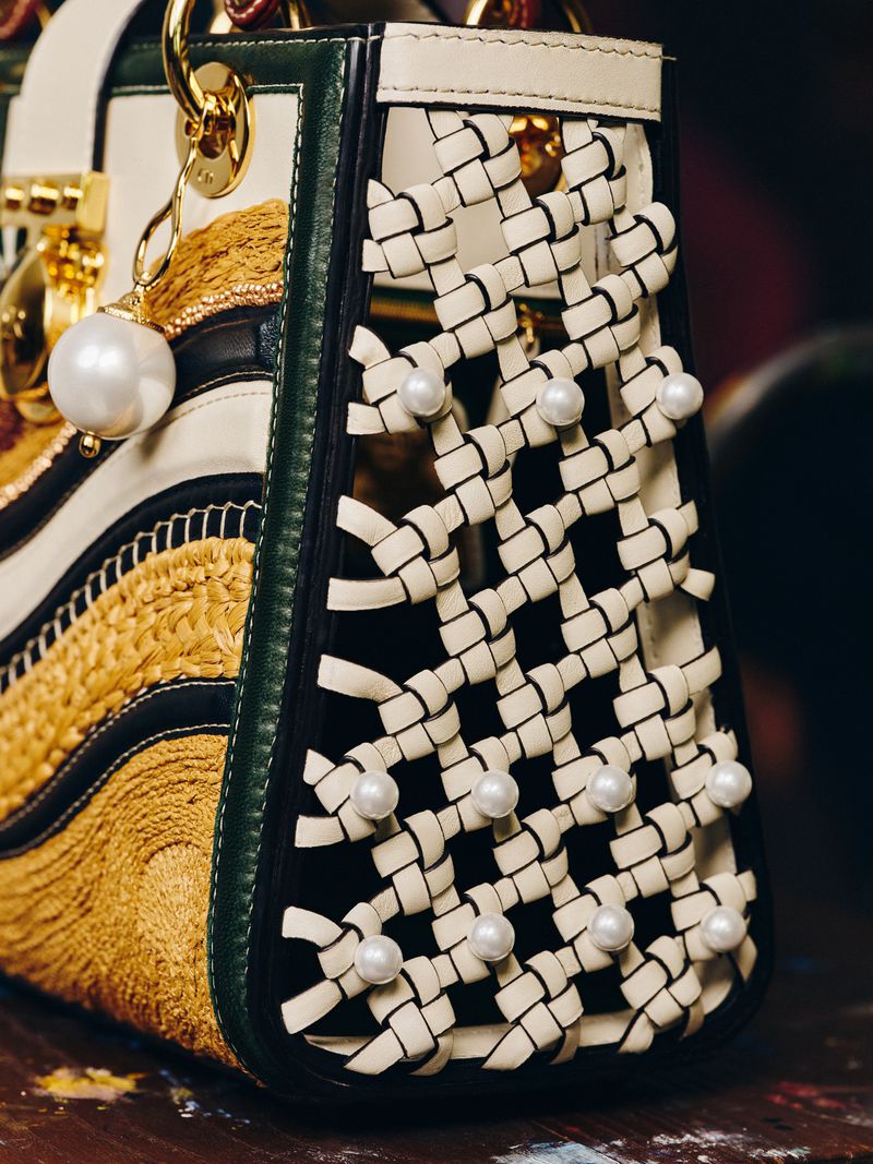 Fashion handbag with pearl embellishments and woven straw design, showcasing luxury accessories and high-end design details.