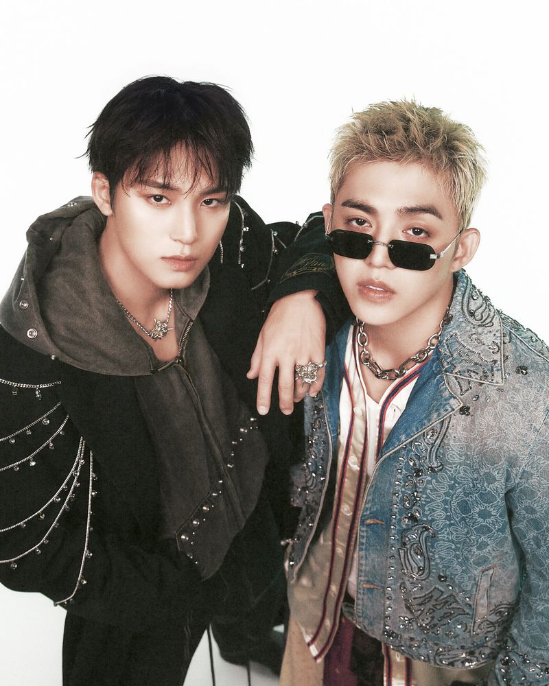 Two stylish Korean pop idols pose in ornate jackets against a white backdrop, showcasing fashion and confident expressions. 