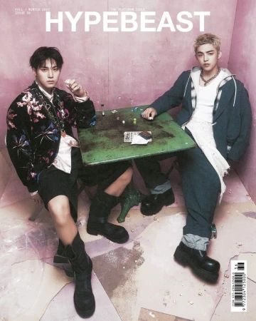 Hypebeast magazine cover featuring two young men seated at a table with a pink wall backdrop and various props, showcasing a fashion editorial.