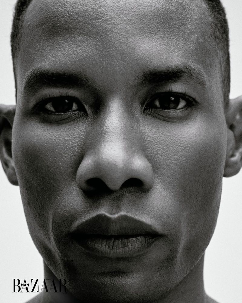 Monochromatic close-up of an African-American adult male face with a neutral expression, set against a bright, clean backdrop with text.