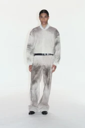 Model Kevin Nyavedji wearing a grey and white tie-dye patterned jacket and matching trousers against a white seamless backdrop.