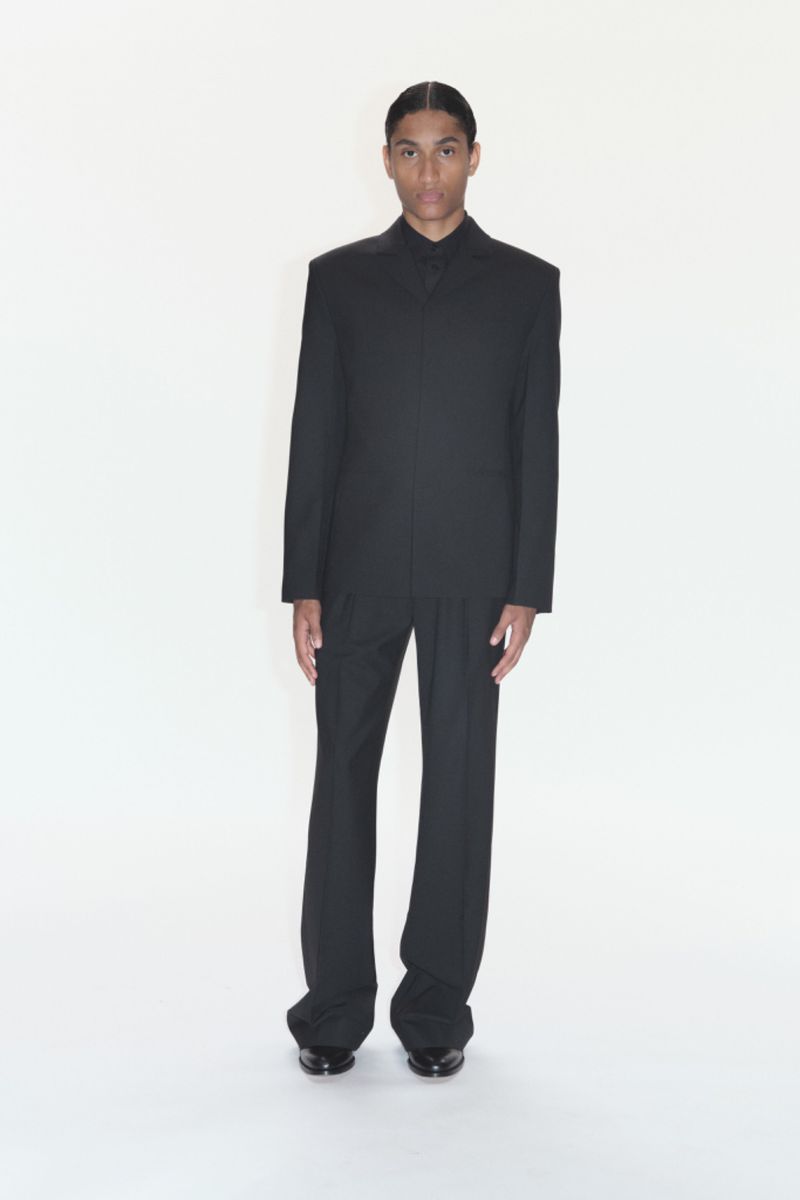 Portrait of a handsome adult male in a tailored black suit against a plain white backdrop, showcasing a sophisticated and formal look.