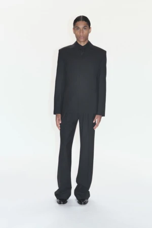 Portrait of a handsome adult male in a tailored black suit against a plain white backdrop, showcasing a sophisticated and formal look.