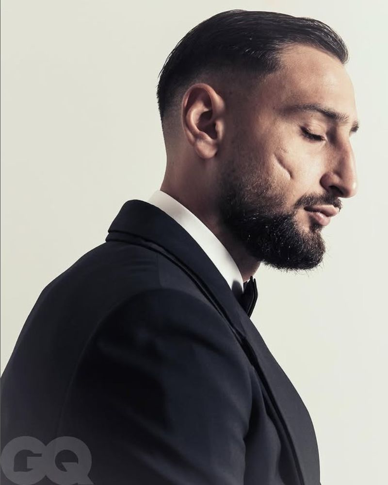 Portrait of adult male in a black tuxedo with a bow tie looking down against a white background, studio lit, shallow depth of field. 