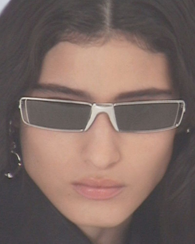 Close-up of an adult woman with straight hair wearing sunglasses with a silver frame and dark lenses, facing the camera.