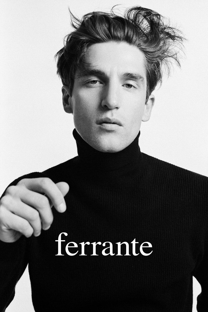 Black and white portrait of a young adult male with tousled hair wearing a black turtleneck sweater, looking directly at the camera.
