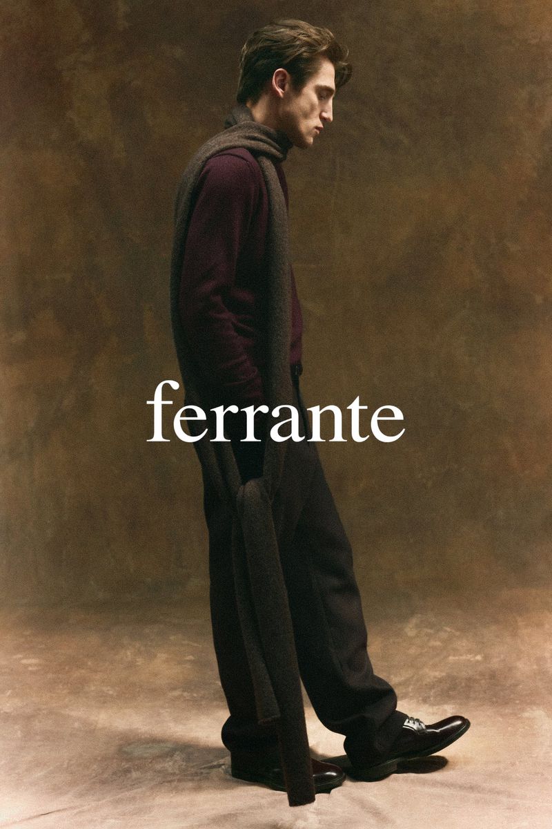 An adult man in a burgundy shirt, dark pants, and black leather dress shoes poses in a studio wearing a scarf. Brand name 'Ferrante' visible.