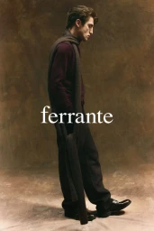 Profile shot of a man wearing a plum sweater, dark trousers, scarf, and loafers against a textured backdrop.