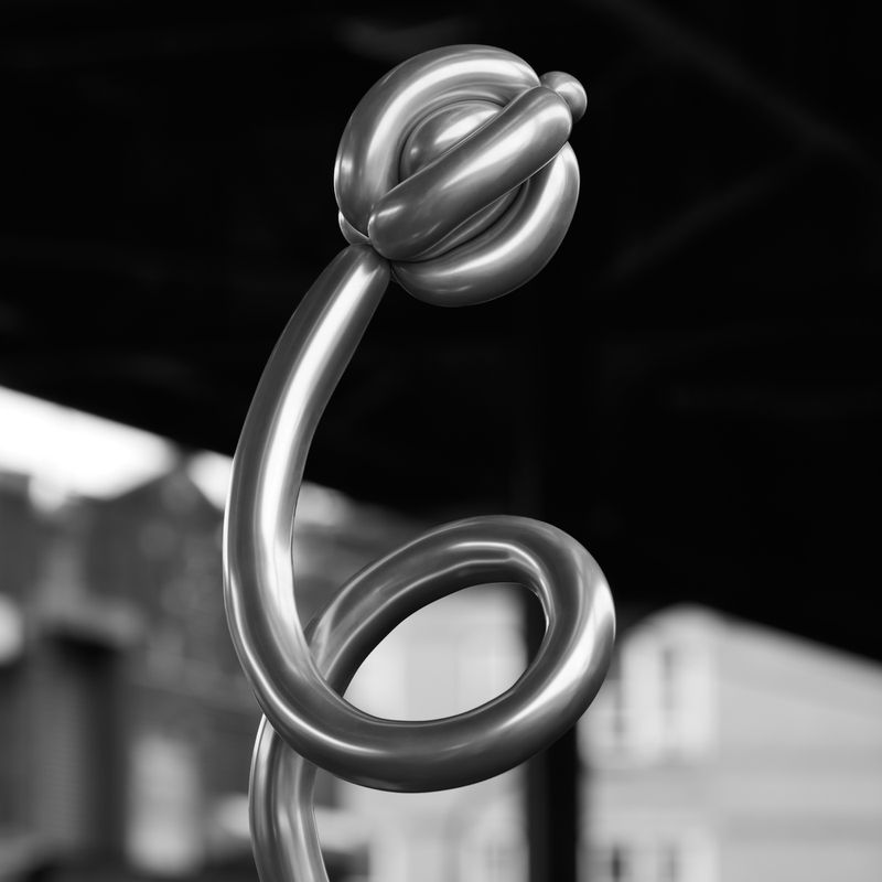 Abstract metal sculpture with curved lines and a spherical knot on top, set against a blurred background in black and white.