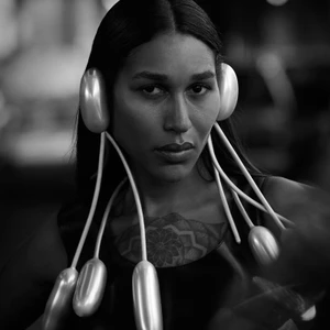 Black and white portrait of a model wearing a surreal sculptural headpiece made of inflated balloon tubes framing the face.