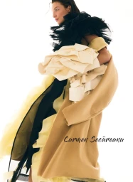 Model wearing layered sculptural garments in black, cream, and camel against a bright white background for Elle Romania.