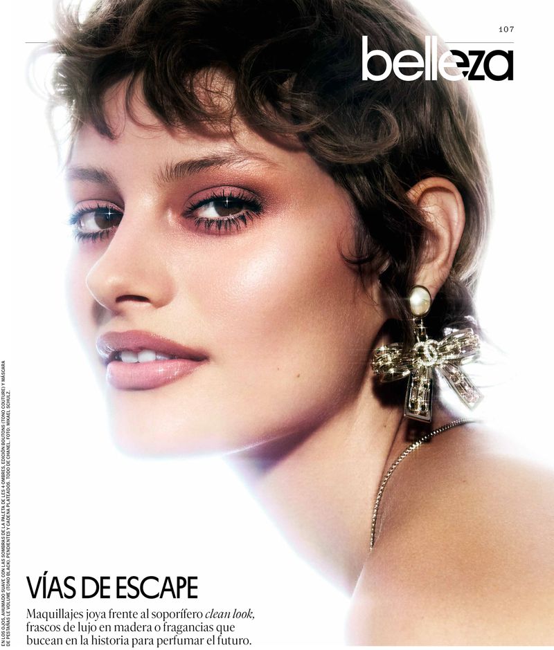 Close-up of a woman with short brown hair, wearing large earrings, with a magazine cover featuring the word 'belleza' visible.
