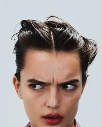 Close-up portrait of a model with styled dark hair and subtle red lipstick against a plain light background for Marie Claire France.