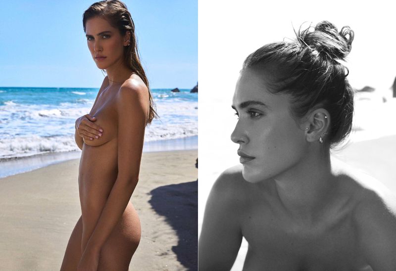 Nude woman with hand covering breasts on sandy beach with blue ocean and sky background; side profile close-up in black and white.