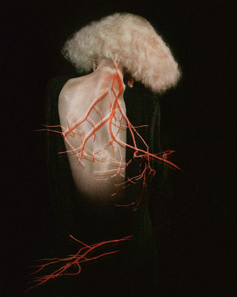 Conceptual image of a person's back and head with red, root-like structures against dark backdrop; artistic and visually striking.