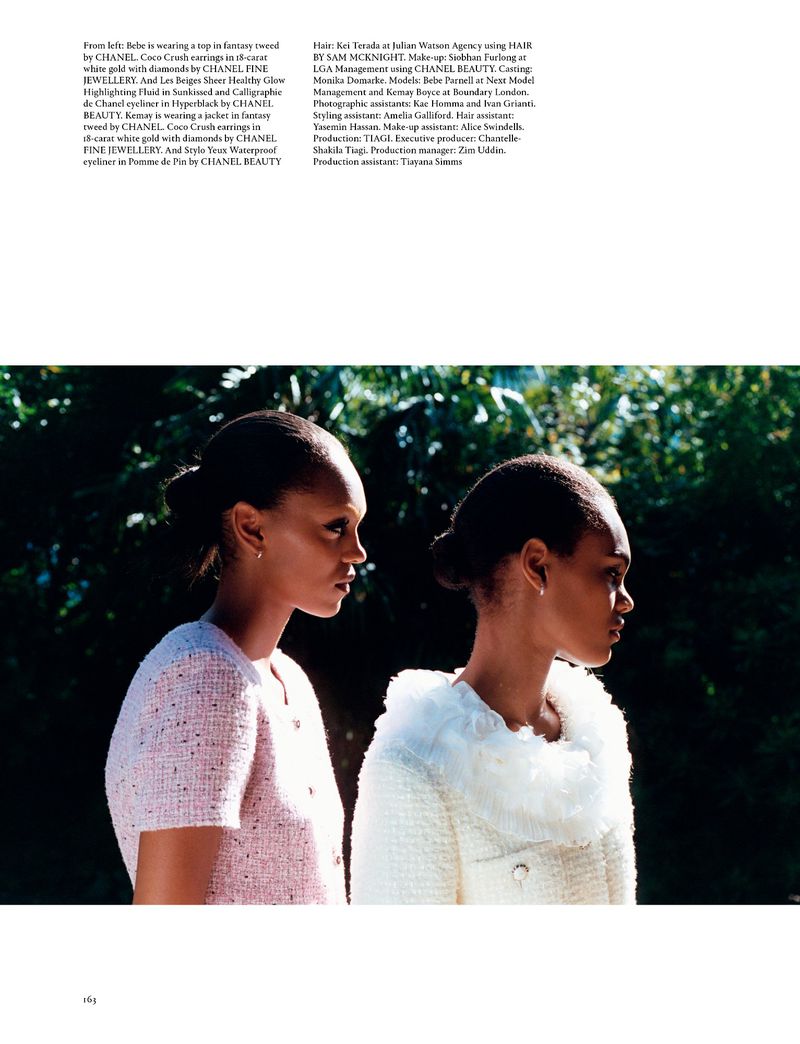 Two dark-skinned young women in jackets stand outdoors in a medium shot, side view. Fashion editorial with soft, natural light.