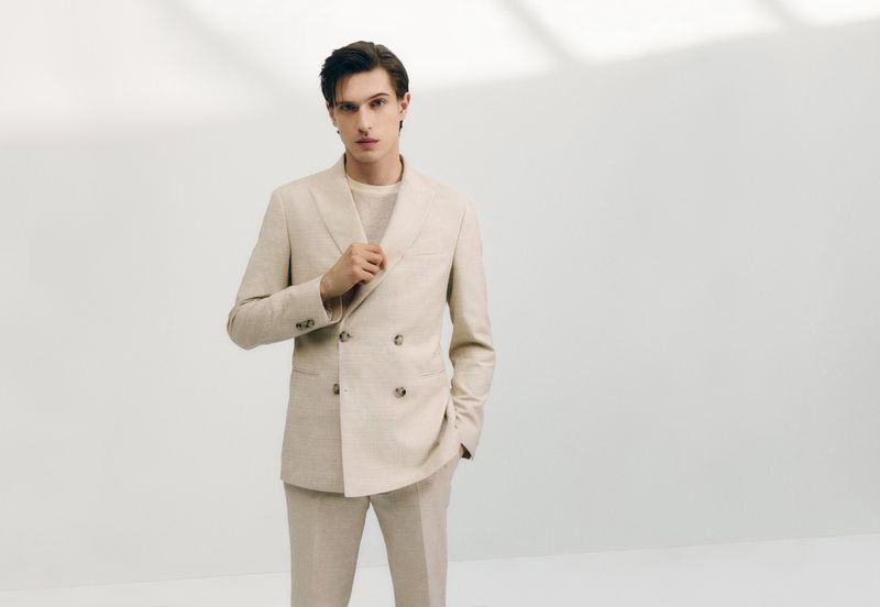 Model Edoardo Sebastianelli wearing a cream double breasted suit against a white seamless studio background for BOSS.